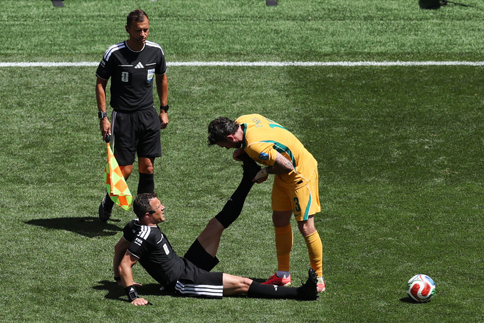 Trọng tài Felix Zwayer được tiền vệ Australia Aiden ONeill (áo vàng) hỗ trợ căng cơ trong trận Mỹ thắng Australia 2-0 ở lượt hai bảng D World Cup 2026, trên sân Seattle ở Mỹ ngày 19/6/2026. Ảnh: AP