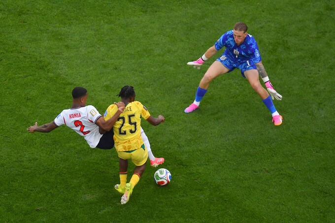 Prince Adu (số 25) áp sát trong tình huống Ezri Konsa phá bóng trước khung thành Anh, với Jordan Pickford băng ra hỗ trợ. Ghana cho rằng Konsa phạm lỗi với Adu trong một pha bóng gây tranh cãi ở trận hòa 0-0 tại bảng L World Cup 2026 trên sân Boston. Ảnh: AP