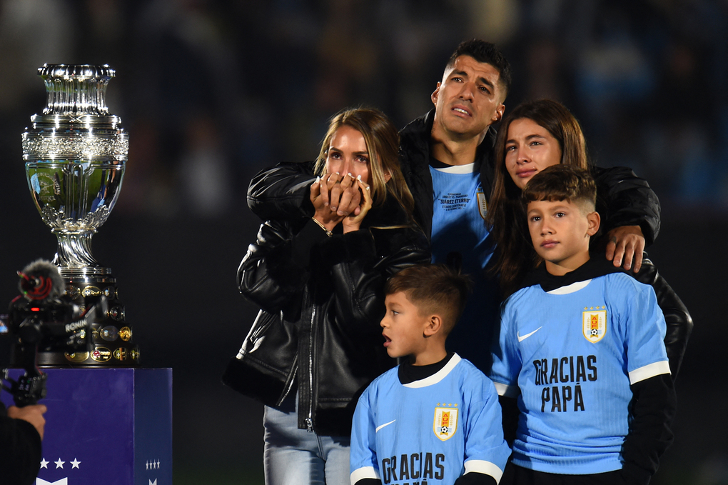 Suarez khóc khi đứng cạnh vợ Sofia Balbi (trái) và các con Delfina (phải), Lautaro (giữa), và Benjamin bên bản sao cup vô địch Copa America trong buổi lễ tri ân anh ở trận đấu cuối cùng cho tuyển Uruguay trên sân Centenario, Montevideo ngày 6/9/2025. Ảnh: AFP