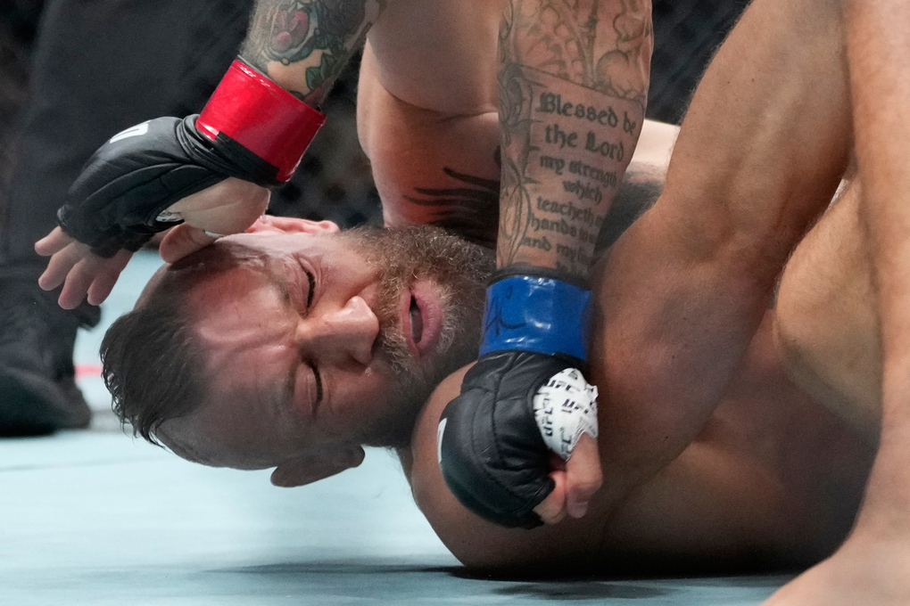 Conor McGregor nằm sàn và nhận đòn từ Max Holloway. Ảnh: AP