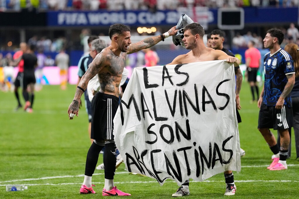 Tiền vệ Giovani Lo Celso cầm biểu ngữ với dòng chữ Quần đảo Malvinas thuộc về Argentina, ám chỉ quần đảo Falkland, trong khi đồng đội Nicolas Otamendi ra hiệu với anh sau trận bán kết World Cup giữa Anh và Argentina trên sân Atlanta, Mỹ ngày 15/7. Ảnh: AP