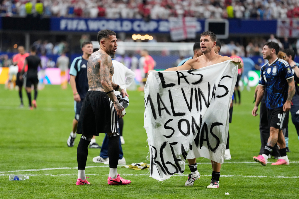 Giovani Lo Celso của Argentina cầm biểu ngữ ghi Quần đảo Malvinas là của Argentina, ám chỉ quần đảo Falklands, trong khi đồng đội Nicolas Otamendi tiến đến sau trận thắng Anh 2-1 ở bán kết World Cup 2026 trên sân Atlanta ngày 15/7. Ảnh: AP