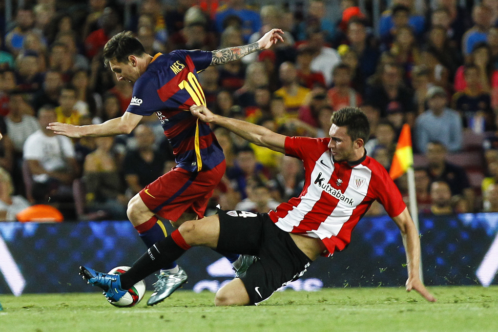 Lionel Messi (trái) tranh chấp bóng với hậu vệ Aymeric Laporte trong trận lượt về Siêu Cup Tây Ban Nha giữa Barca và Athletic Bilbao trên sân Camp Nou, Barcelona ngày 17/8/2015. Ảnh: AFP