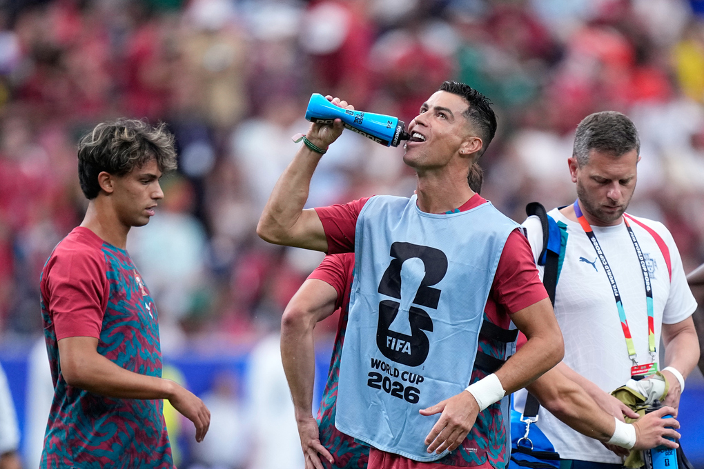 Cristiano Ronaldo uống nước bên cạnh Joao Felix trong lúc khởi động trước trận Bồ Đào Nha gặp Uzbekistan ở bảng K World Cup 2026 trên sân Houston ngày 23/6. Ảnh: AP